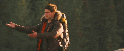 Man With Backpack Standing in Woods Arms Outstretched