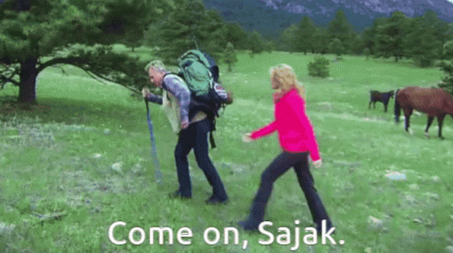 Man With Backpack Walking With Woman In Field With Horses GIF