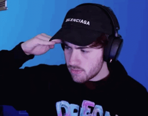 Man with Balenciaga Hat and Headphones Looks at Camera