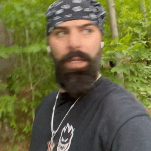 Man With Beard and Bandana Walking Through Woods