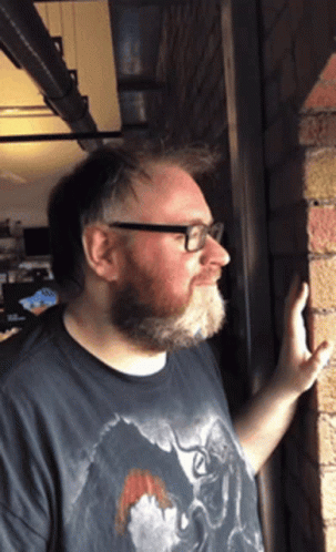 Man With Beard and Glasses Leaning Against Wall