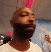 Man with Beard and White Shirt in Front of Exit Sign