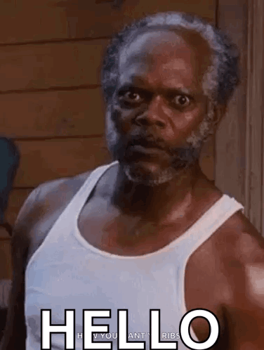 Man With Beard and White Tank Top in Front of Wooden Wall