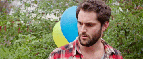 Man With Beard Holding Blue And Yellow Balloon GIF
