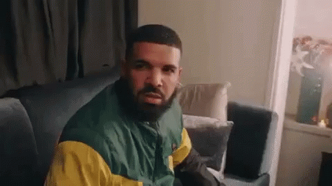 Man With Beard in Green and Yellow Jacket Sitting on Couch