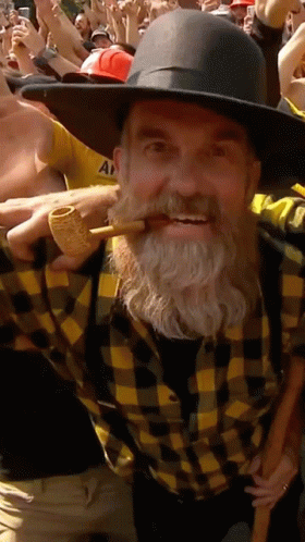 Man With Beard in Plaid Shirt and Hat Holding Pipe