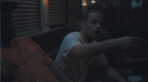 Man With Beard In White Shirt Sitting In Dark Room GIF