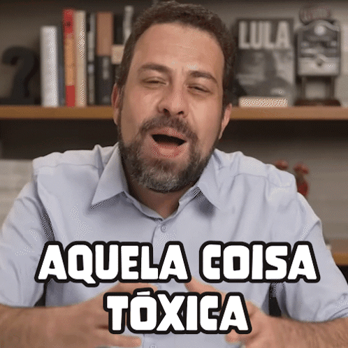 Man With Beard Says Aquela Coisa Toxica in Front of Bookshelf
