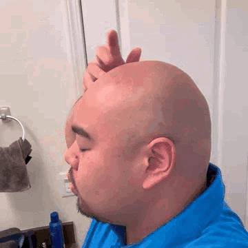 Man With Beard Shaving Head in Bathroom Mirror