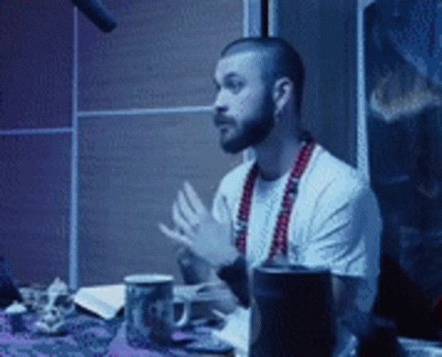 Man With Beard Sitting at Table With Microphone