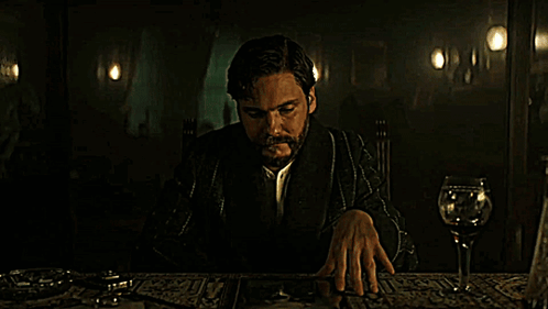 Man With Beard Sitting at Table With Wine Glass