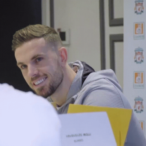 Man With Beard Smiling in Front of Liverpool FC Sign