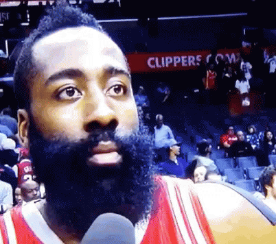 Man With Beard Talking Into Microphone in Front of Clippers.com Sign