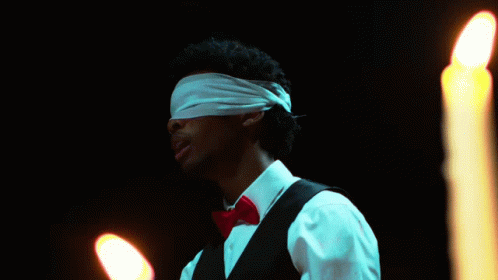 Man With Blindfold In Front Of Candles GIF