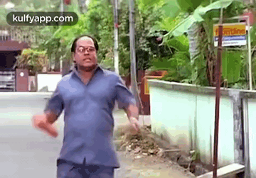 Man With Blue Shirt and Glasses Walking Street