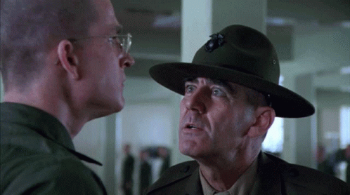 Man With Bug Hat Talks to Man in Military Uniform