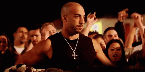 Man With Cross Necklace Standing in Front of Crowd