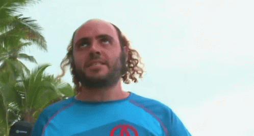 Man With Curly Hair and Beard in Blue Shirt With Red Circle
