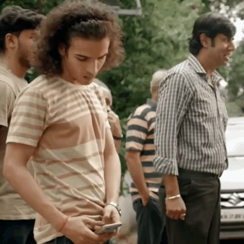 Man With Curly Hair Checking Phone in Line