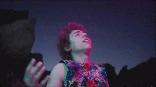Man With Curly Hair In Front Of Purple Blue Background GIF