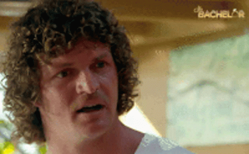 Man With Curly Hair in White Shirt Looking at Something