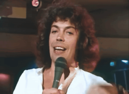 Man With Curly Hair Singing Into Microphone