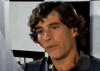 Man With Curly Hair Sitting In Front Of Checkered Wall Talking GIF