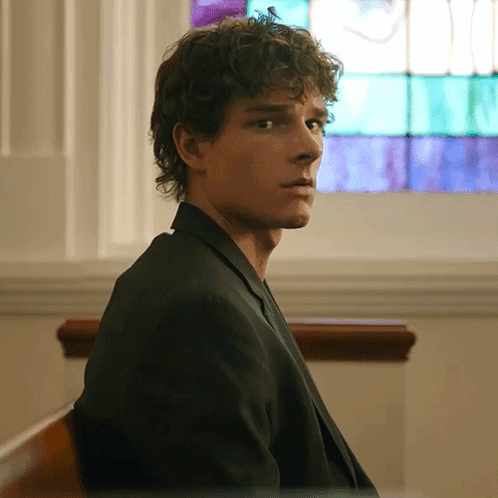 Man With Curly Hair Sitting in Front of Window
