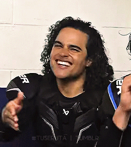 Man with Curly Hair Smiling in Black Shirt