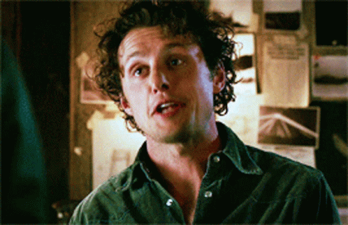 Man With Curly Hair Standing in Front of Wall With Papers