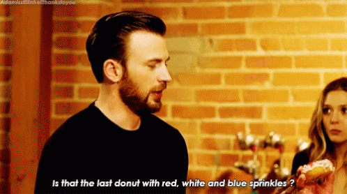 Man With Donut Talking to Woman in Front of Brick Wall