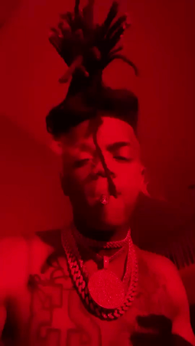 Man With Dreadlocks And Necklace Smoking In Red Room GIF