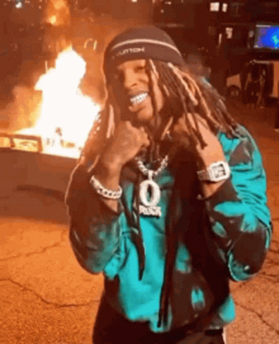 Man With Dreadlocks by Fire in Parking Lot