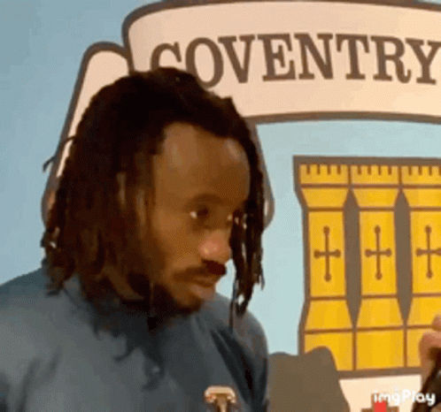 Man With Dreadlocks in Front of Coventry Sign