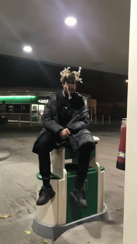 Man with Dreadlocks Sitting on Trash Can