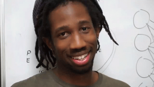 Man With Dreadlocks Smiling in Front of PE Board