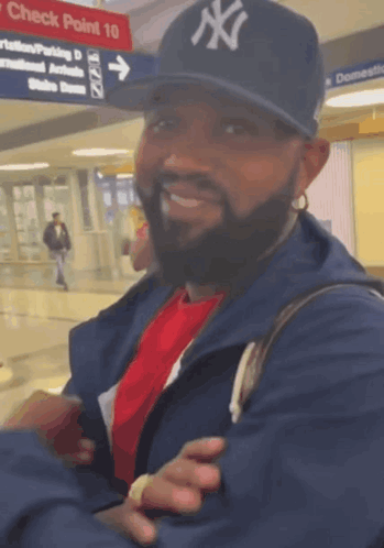 Man With Earbuds Smiling Beside Blue Stuffed Animal