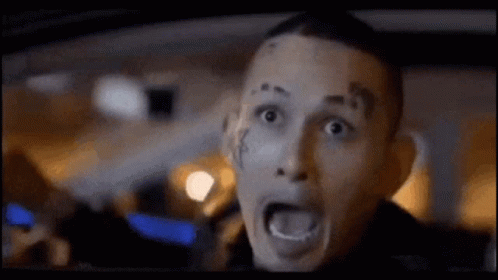 Man With Face Tattoo Driving Car Mouth Open