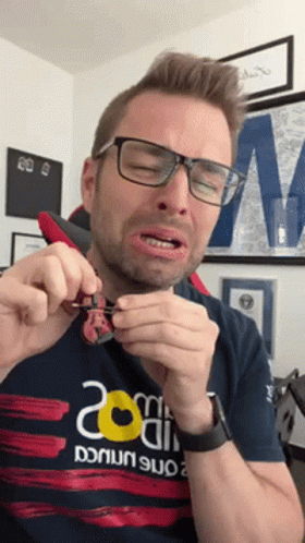 Man With Glasses And 20 Shirt Holding Something GIF