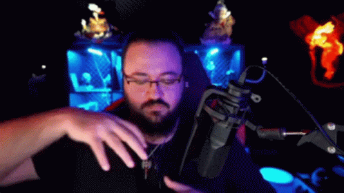 Man With Glasses and Beard at Microphone in Dark Room