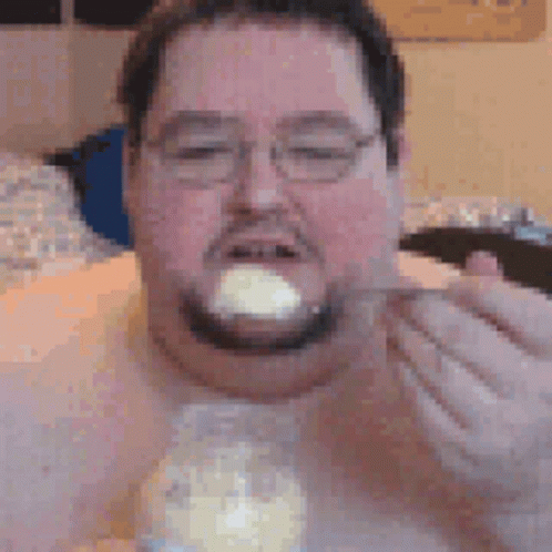 Man With Glasses and Beard Eating From Jar With Spoon