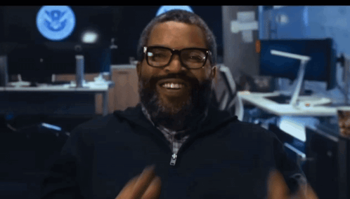 Man With Glasses And Beard Smiling Before U.S. Department Of Homeland Security Sign GIF