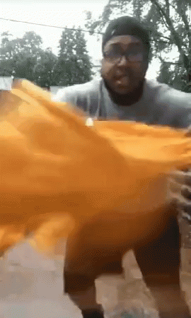 Man With Glasses And Hat Holding Orange Cloth GIF