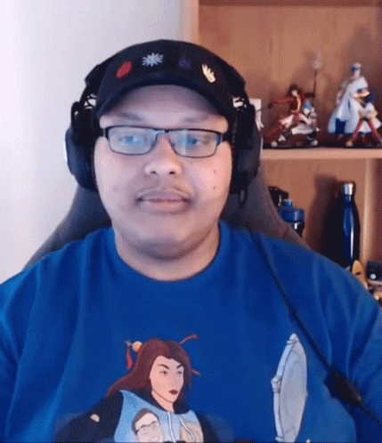Man With Glasses and Headphones in Front of Shelf With Figurines