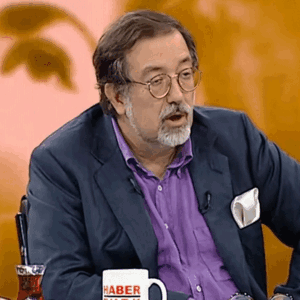 Man With Glasses and Purple Shirt Holding Cup Saying Haber