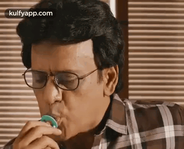 Man With Glasses Eating Green Candy At Table GIF