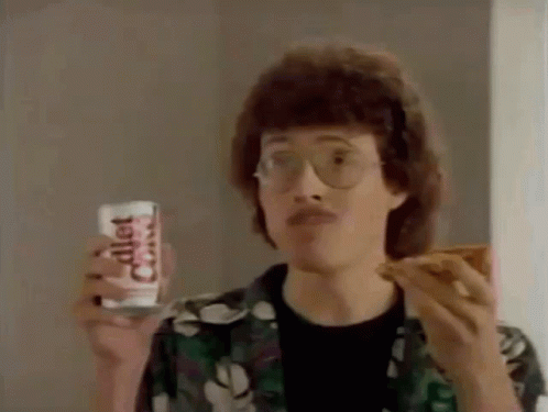 Man with Glasses Eating Pizza and Holding Diet Coke