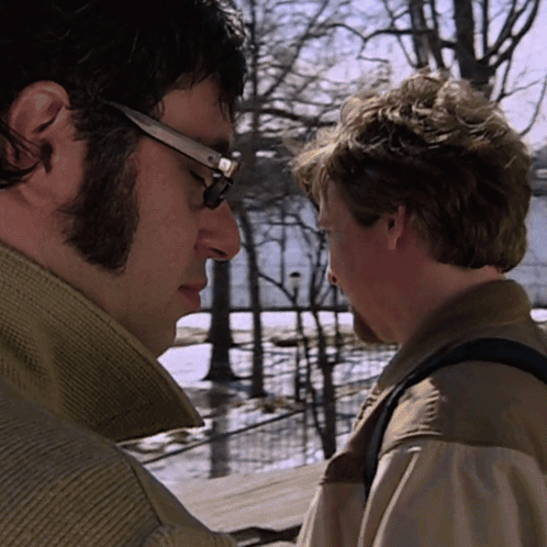 Man With Glasses Looking at Another Man