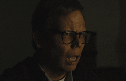 Man with Glasses Making Funny Face in Dark Room