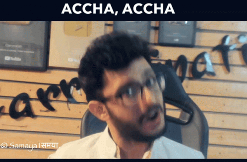Man With Glasses Sitting in Front of Accha Accha Wall